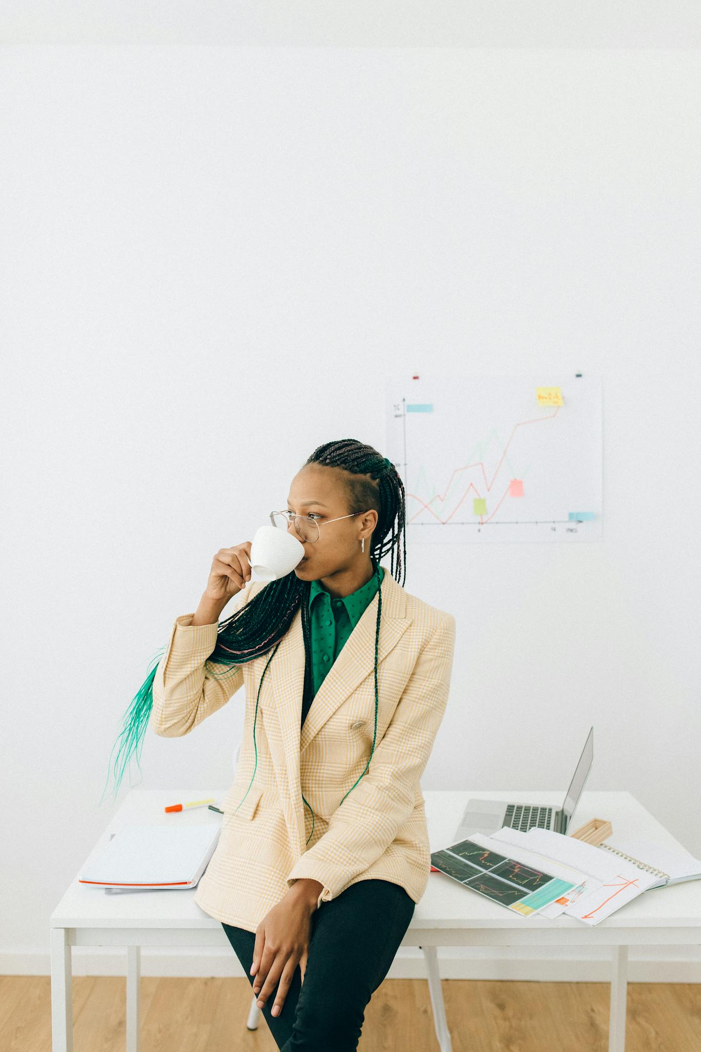 Businesswoman enjoying coffee while analyzing data at a desk.